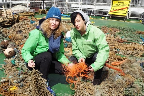 82.1 (c) Greenpeace marine expert Sandra Schöttner (left) and spokesperson Melanie Aldrian in the midst of the recovered ghost nets. Among the nets are the particularly dangerous orange dolly ropes. (c) Olaf Klodt