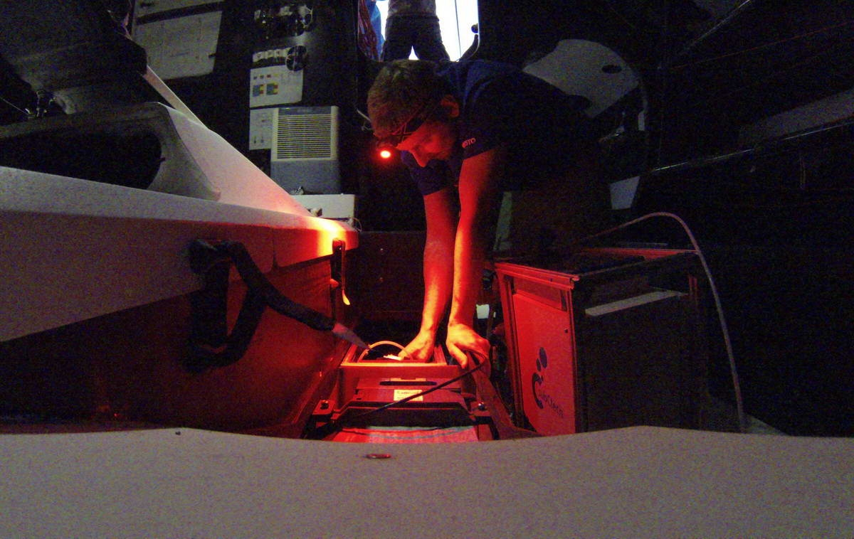 Sören Gutekunst installs a sensor in the hull of the yacht 