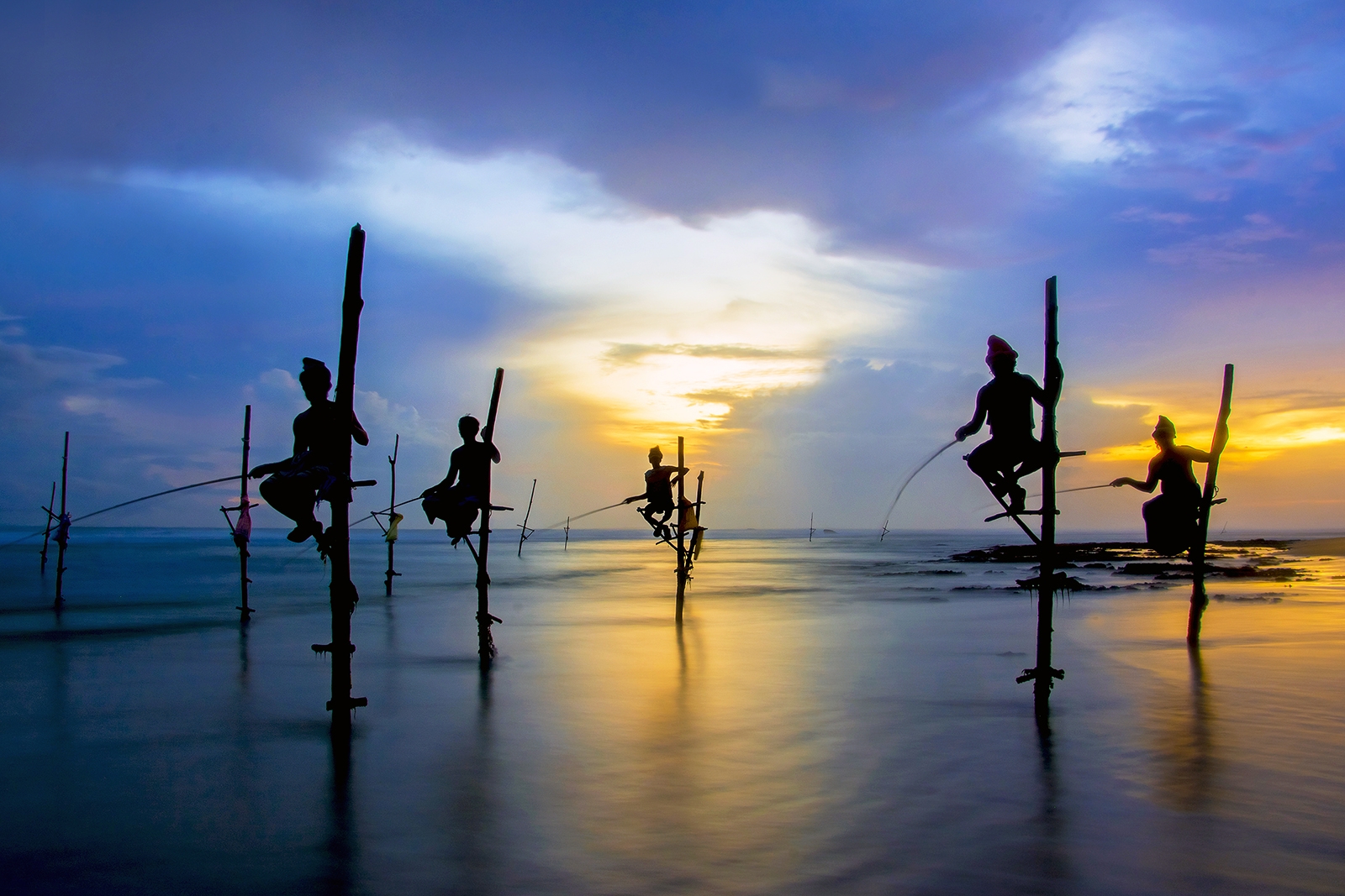 Silhouettes of the traditional Sri Lankan stilt fishermen on a s